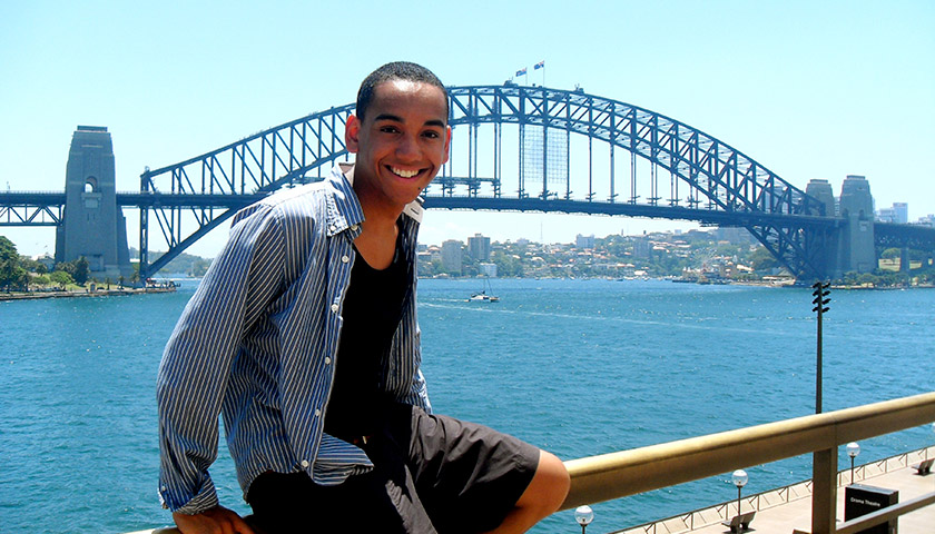 A student in Australia sitting by the water in front of a bridge.