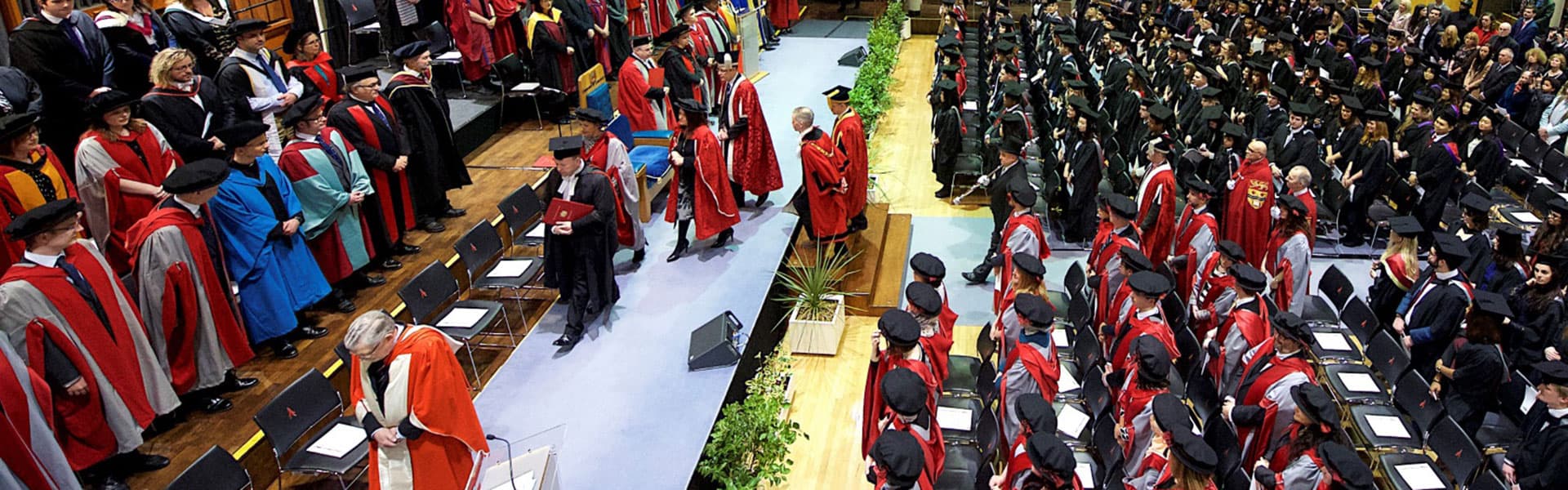 A graduation ceremony seen from overhead, with people in colourful robes and rows of students